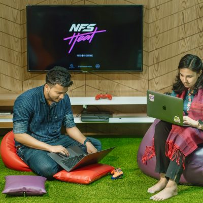 a man and a woman sitting on bean bag chairs looking at a laptop